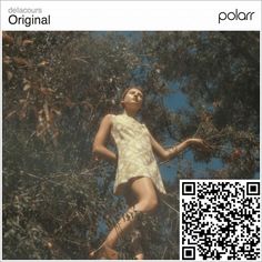 an image of a woman standing in the woods looking up at trees with qr code on it