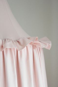 a pink dress with ruffles is hanging on a hanger in front of a white wall