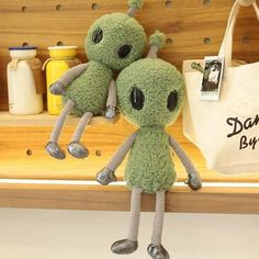 two green stuffed animals sitting on top of a shelf