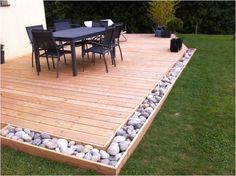 a wooden deck with rocks and chairs on it