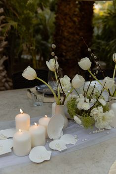 white flowers and candles sit on a table