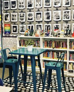 two blue chairs sitting at a table in front of a book shelf filled with books