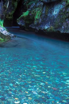 the water is crystal blue and clear in this canyon stream that runs between two large rocks