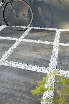 a bicycle parked next to a wall with gravel on the ground and rocks in front