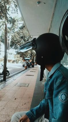 a person wearing a motorcycle helmet sitting on the side of a road next to a building