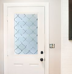 a white door with a decorative glass paneled in to the side and black knobs