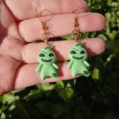 a pair of green zombie earrings on a person's hand