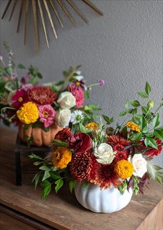 two white pumpkin vases filled with colorful flowers