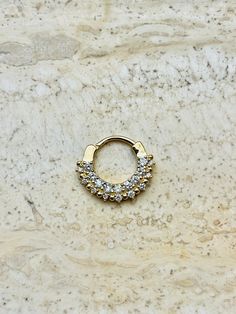 an image of a gold nose ring with diamonds on it's side, sitting on a marble surface