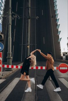 two people are dancing on the street in front of a traffic light and an overpass