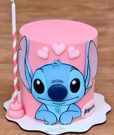 a pink and blue cake with a little stitcher on it's side, next to a candle