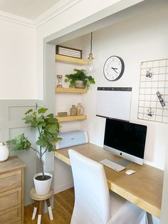 a desk with a computer on top of it and a potted plant next to it