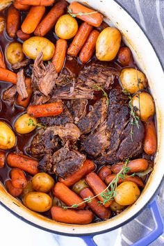 pot roast with carrots, potatoes and meat in a blue pot on a table