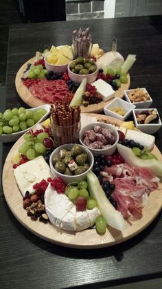 a table topped with plates filled with different types of cheese and meats on top of wooden platters