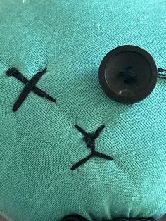 two black crosses on a green cushion with buttons in the shape of jesus's cross