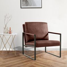 a brown chair sitting in front of a white wall next to a table with a vase on it