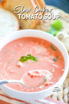 a spoon full of soup with bread in the background and text overlay reading slow cooker tomato soup