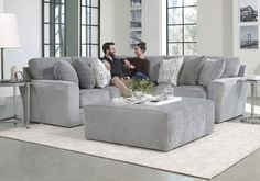 two people sitting on a gray couch in a living room