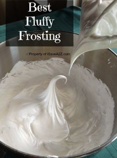 a metal bowl filled with white frosting on top of a table