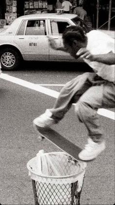 a man riding a skateboard over a trash can