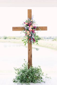 a cross decorated with flowers and greenery