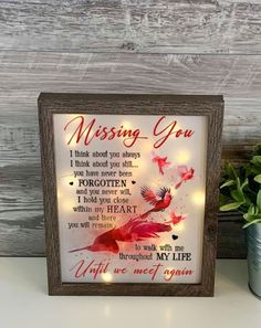 a sign that says missing you with some lights on it and a potted plant next to it