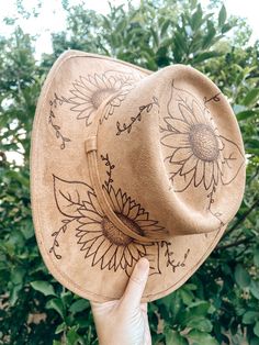 "Cowgirl Hat - \"Sunflowers\" | Autumn Fashion | Fall Wedding Hat | Pyrography Hat Art | Vegan Suede From the artist: The design for this hat reminds me of a warm summer nights out in the country and is perfect to wear to your local summer concert series where the local band plays on weekend nights, kids chase each other in the night air, and you get to feel like a kid yourself again. The sunflowers are in full bloom out beyond the dark and, while the weather may be hot, the cold drinks keep everything cool. Every time you wear this hat you can feel like you're out on a country, kicking up the dust as you dance and sing the night away and feel like a teenager again. Cowgirl hats featured are light tan but also come in: - Ivory - Cappuccino Taupe All designs are original and drawn by hand b Hat Art, Local Bands, Wedding Hat, Vintage Cowgirl, Cowgirl Hat, Concert Series, Summer Concert, Cowgirl Hats, Wedding Hats