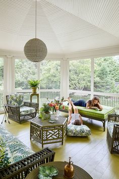 a woman laying on top of a green couch in a living room filled with furniture