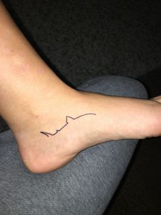 a woman's foot with a small heartbeat tattoo on her left side calf area