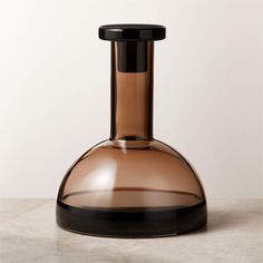 a brown glass vase sitting on top of a white counter next to a black base