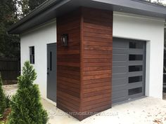 a garage with a wooden roof and two doors on the side of it, in front of some bushes