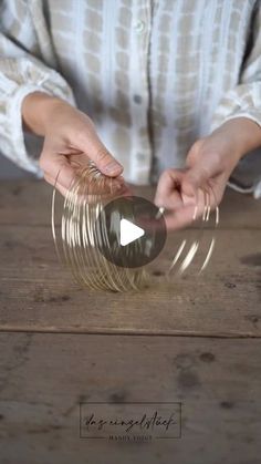 a person is holding some glass on top of a wooden table and touching it with their hands