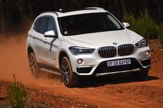 a white bmw suv driving down a dirt road