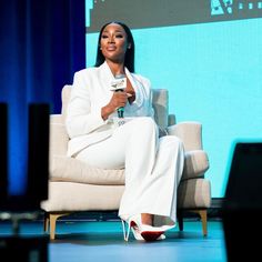 a woman is sitting on a chair and smiling while holding a microphone in her hand