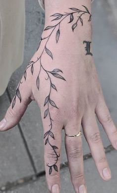 a woman's hand with leaves on it and the letter f painted on it