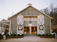 an old barn with wreaths on the doors and windows