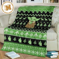 the child yoda blanket is on top of a couch in front of a bookshelf