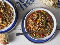 two bowls of soup with bread on the side