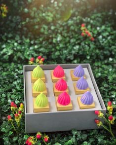 there is a tray that has different colored cookies on it and flowers in the background