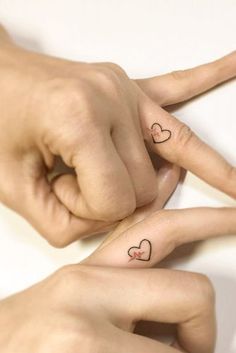 two hands with heart tattoos on their fingers