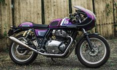 a purple and black motorcycle parked next to a wooden fence