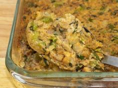 a casserole dish with broccoli and stuffing being spooned into it