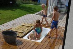 three children are playing in the water on a wooden deck with a bucket and pail