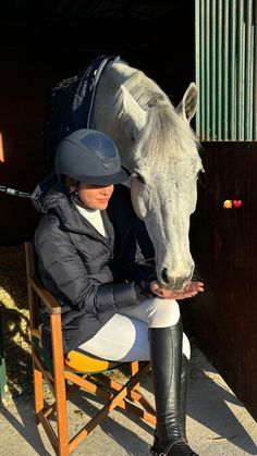 a woman sitting in a chair next to a horse