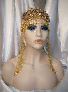 "This 1920s style headpiece is extravagant in every way. It features a classic 20s style Juliet cap constructed of gold beadwork that is strung with fine elastic, providing stretch and comfort. Along its lower edge are 9 1/2\" lengths of bright beaded strands. An expansive bead and sequin appliqué add panache and glamour to this piece. It is a true show stopper. Headpiece will fit a 21\"- 24\" head size All items are made in a smoke and pet free environment *ALL SALES ARE FINAL. I DO NOT ACCEPT Gold Crown Headpiece For Carnival, Gold Costume Hat With Tall Crown For Parties, Gold Ceremonial Headpiece With Tall Crown, Gold Bohemian Party Hat, Bohemian Gold Party Hat, Vintage Gold Crown Headpiece, Fitted Gold Carnival Costume Hat, Adjustable Gold Costume Hats And Headpieces For Carnival, Fitted Gold Costume Hat For Carnival