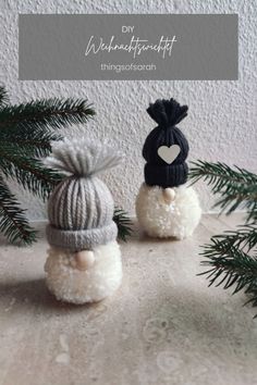 two small knitted snowmen sitting next to each other on top of a table