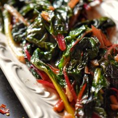 a white plate topped with greens and red onions on top of a black tablecloth