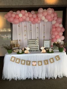 a baby shower table with pink and white balloons