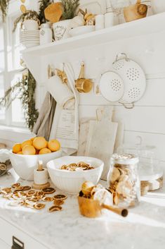 the kitchen counter is full of food and utensils, including oranges in bowls