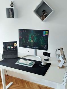 a computer desk with two monitors and a keyboard on it, in front of a white wall